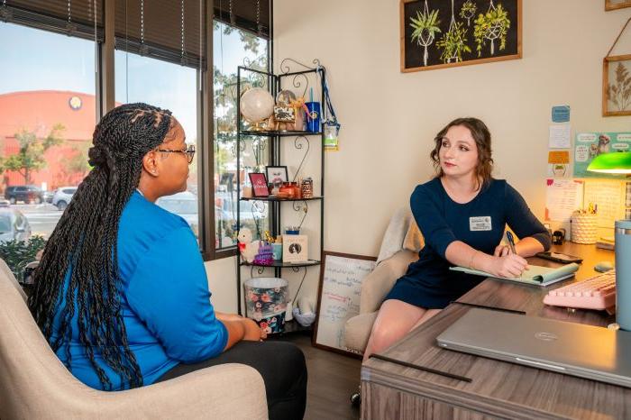 A female student speaking to a female mentor about something in an office.